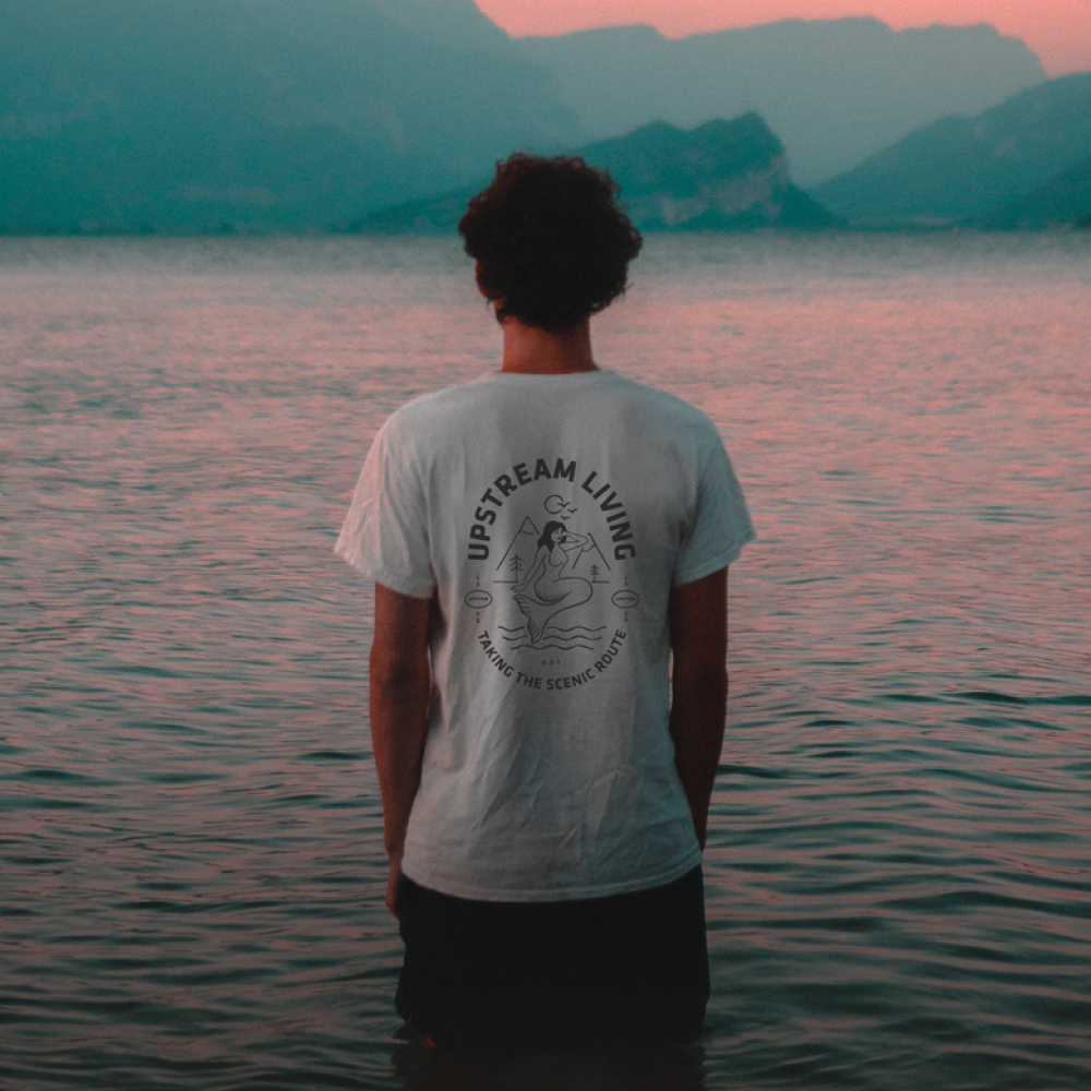 Man standing in the sea wearing an upstream living t-shirt